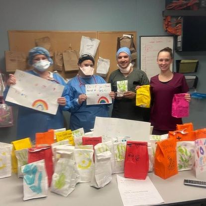 Hospital staff holding decorated snack bags and thank-you drawings made by Millburn kids